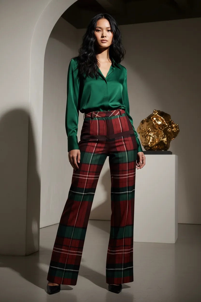 Woman wearing burgundy green tartan trousers women with a green satin blouse standing indoors