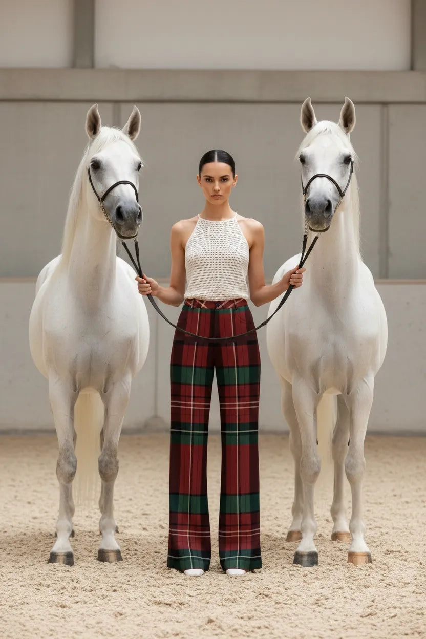 Woman wearing burgundy green tartan trousers women standing between two white horses