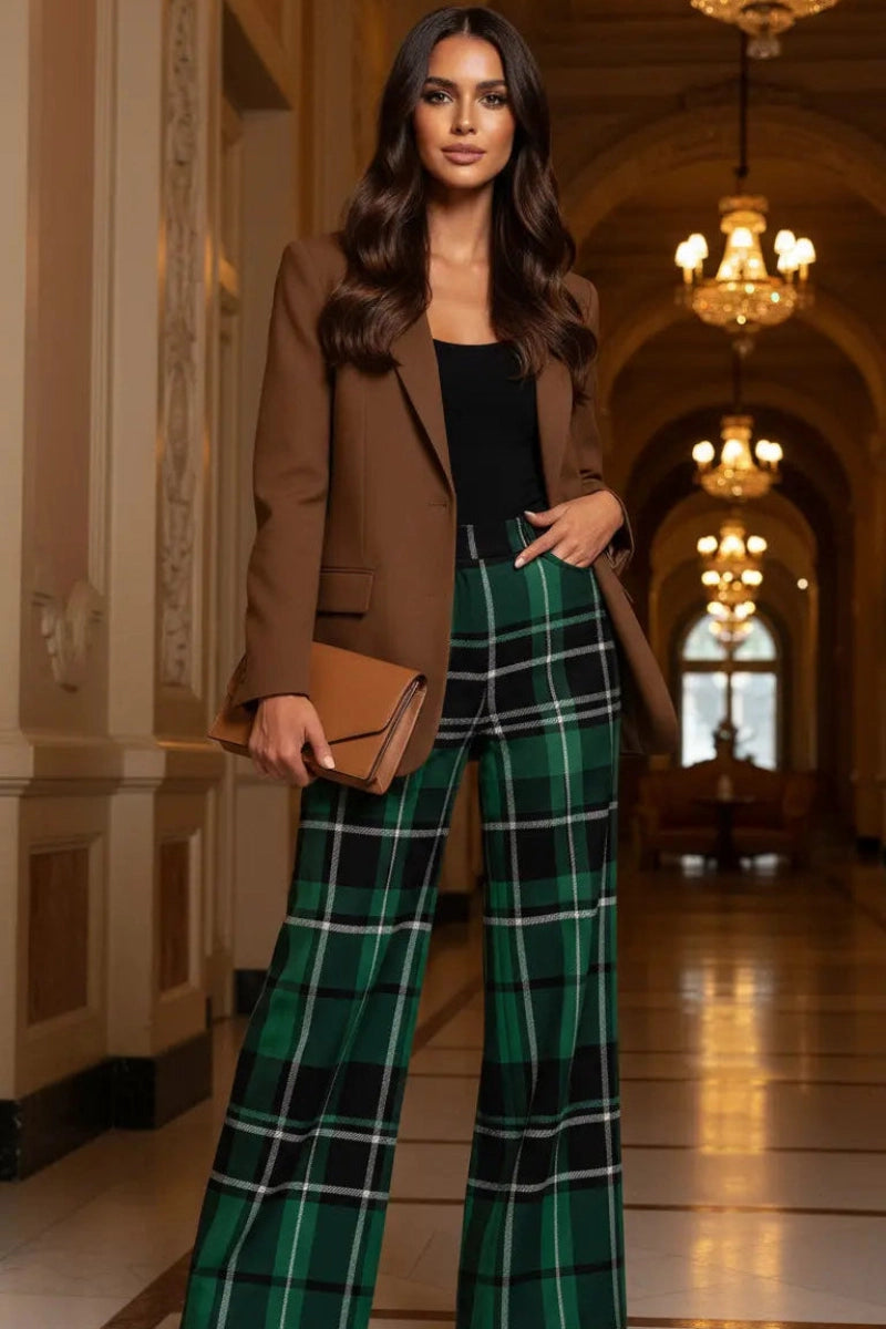Woman wearing green tartan wide leg trousers paired with a brown blazer and tan heels indoors