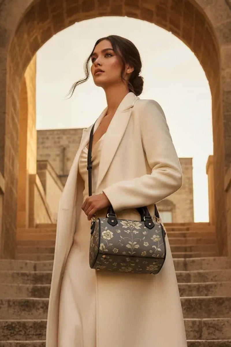 Woman wearing cream coat holding silver floral baroque Crossbody satchel handbag on stone stairs