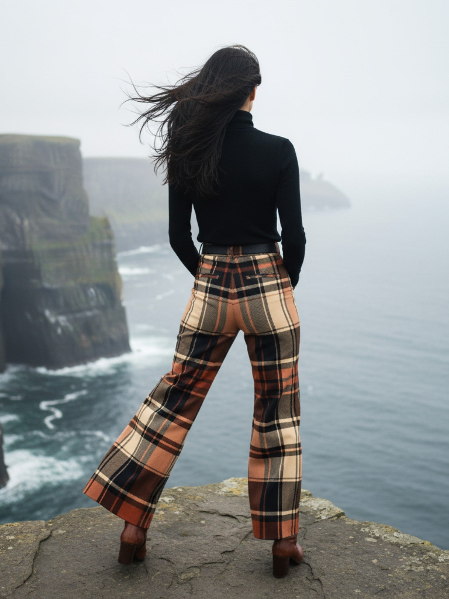 Woman wearing women’s wide leg high waist tartan trousers standing on a cliff overlooking the ocean